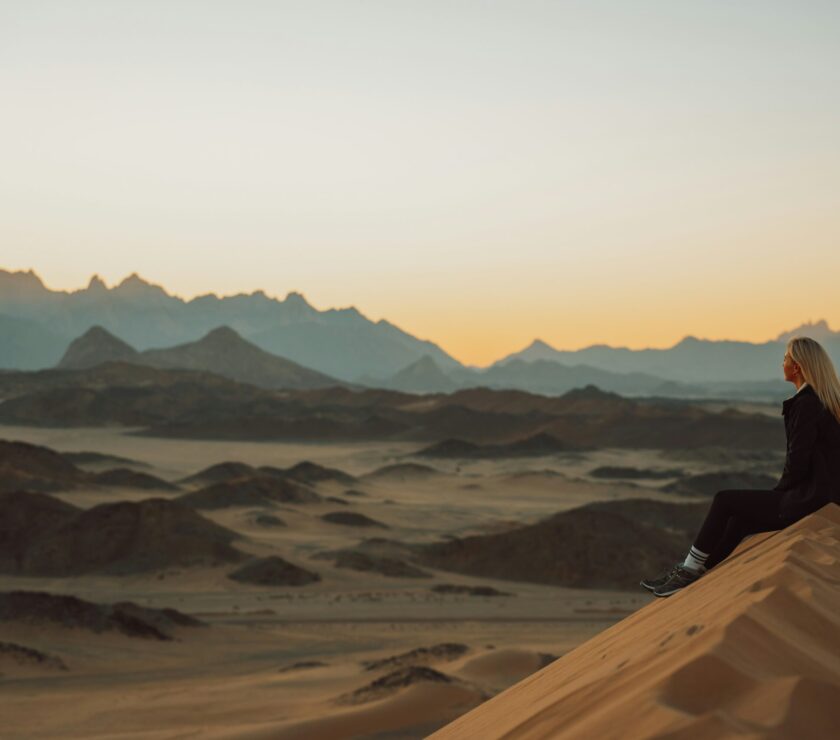 a woman sitting on top of a sand dune