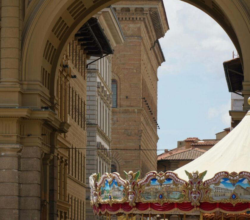 A crowd of people walking down a street under an archway